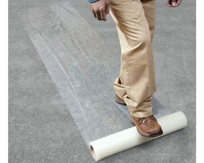 Person rolling out a transparent sheet on a gray floor